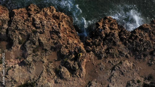 Aerial photography of rocks near the sea. People sitting on a rock near the sea. Sea waves on the beautiful coast of Spain. photo