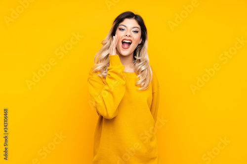 Teenager girl isolated on yellow background with surprise and shocked facial expression