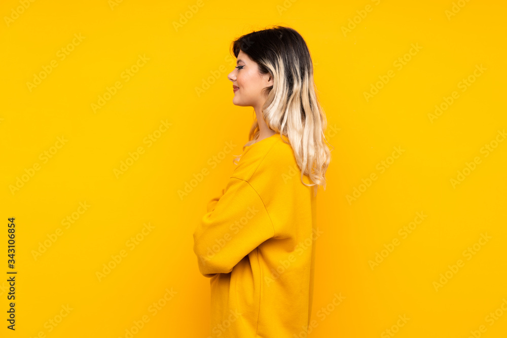 Teenager girl isolated on yellow background in lateral position Teenager girl isolated on yellow background in lateral position