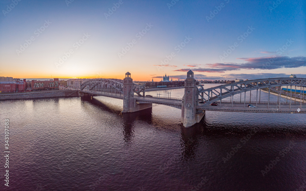 St. Petersburg Russia. Aerial panoramic view from drone to Peter the Great bridge of white nights. Bolsheokhtinsky bridge across the river Neva with evening lighting city with driving cars on highway. St. Petersburg Russia. Aerial panoramic view from drone to Peter the Great bridge of white nights. Bolsheokhtinsky bridge across the river Neva with evening lighting city with driving cars on highway.