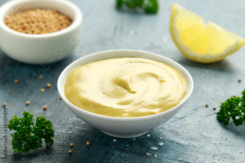 Dijon mustard in white bowl on rustic background