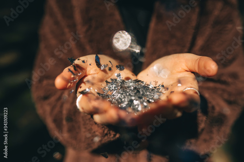Hands of a young woman holding silver glitter