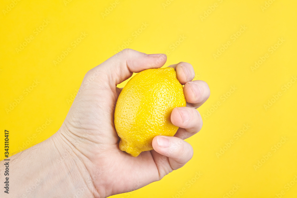Hand holding lemon fruit over yellow background. Close up Hand holding lemon fruit over yellow background. Close up
