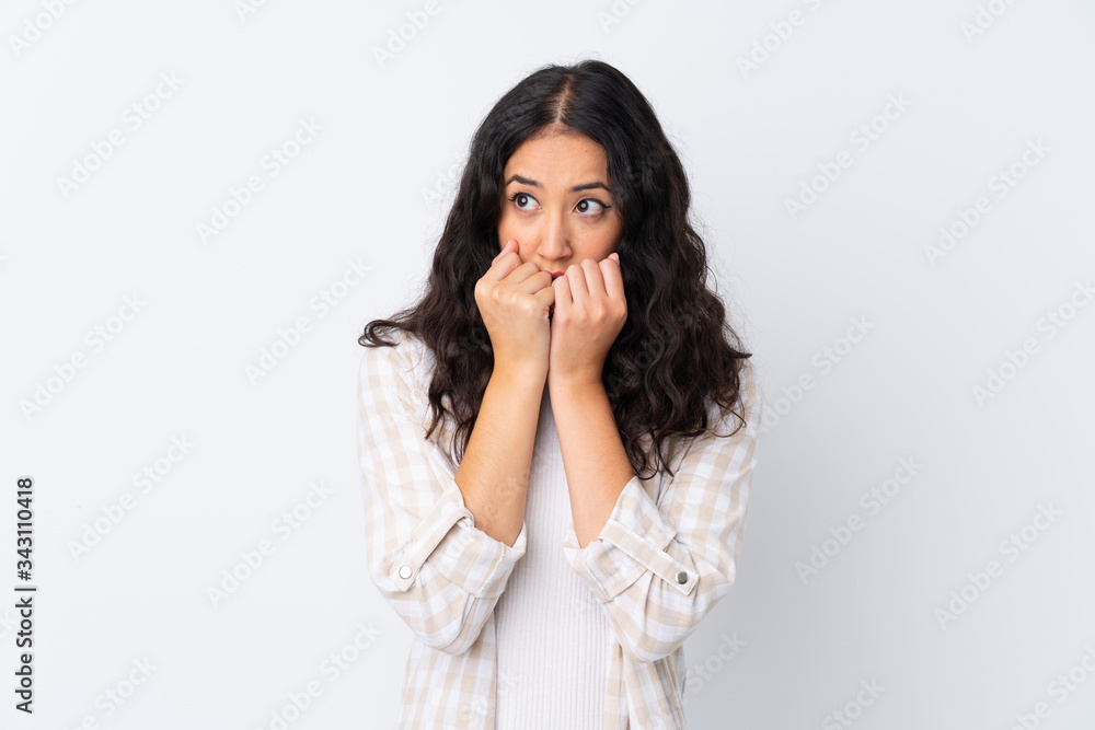 Mixed race woman over isolated white background nervous and scared putting hands to mouth Mixed race woman over isolated white background nervous and scared putting hands to mouth