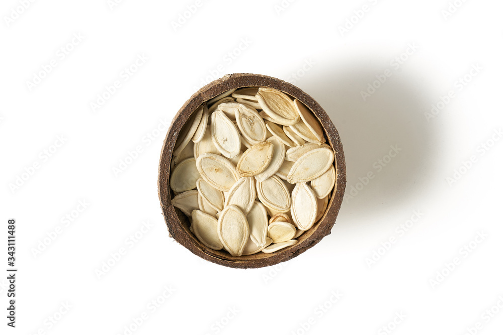 Pumpkin grains in small bowls with coconut on a white background Pumpkin grains in small bowls with coconut on a white background