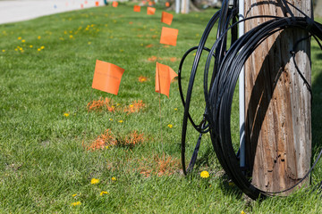 Fiber optic cable, orange marking flags and utility pole. Concept of digging safety, utility locate service and high speed internet