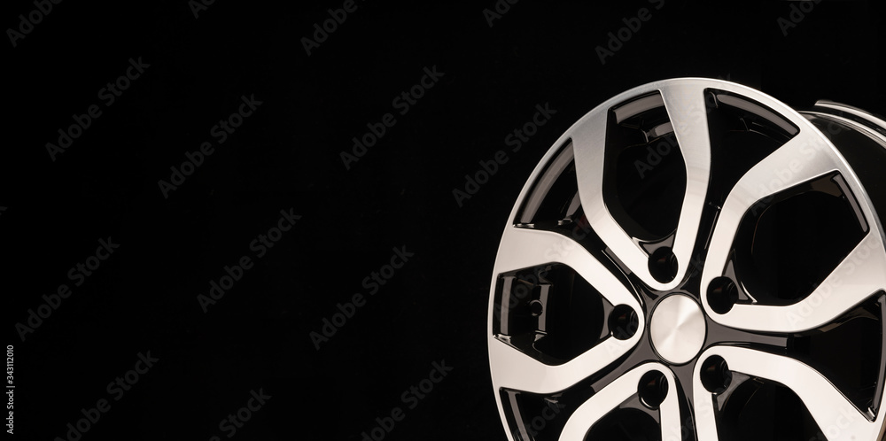 New alloy wheel of the car, close-up on a black background, wheel spokes. beautiful design. copy space. long layout, right location of the objec