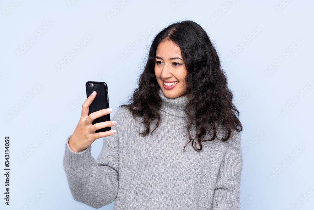 Spanish Chinese woman over isolated blue background making a selfie Spanish Chinese woman over isolated blue background making a selfie
