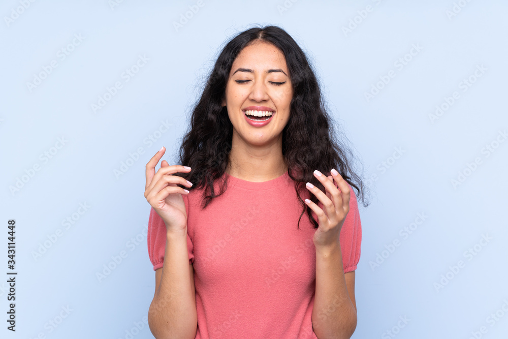 Mixed race woman wearing a sweater over isolated blue background laughing Mixed race woman wearing a sweater over isolated blue background laughing