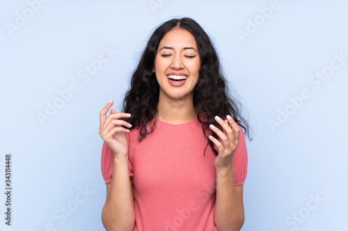 Mixed race woman wearing a sweater over isolated blue background laughing © luismolinero