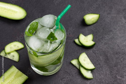 Cooling summer drink with ice and slices of cucumber. Mint and chopped cucumber
