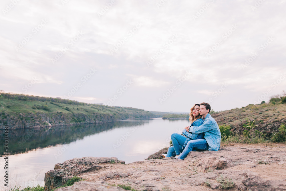 couple in love in blue jeans and white shirts in nature, where the field and rocks