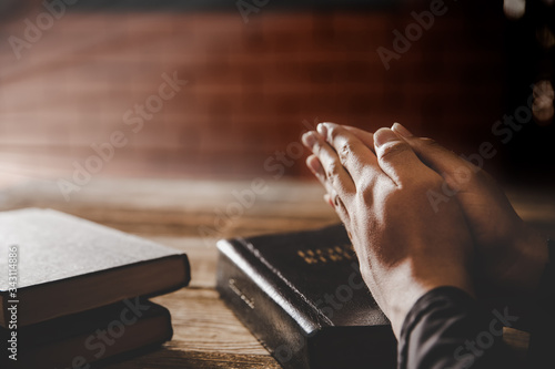 Praying hands of man on old bible.