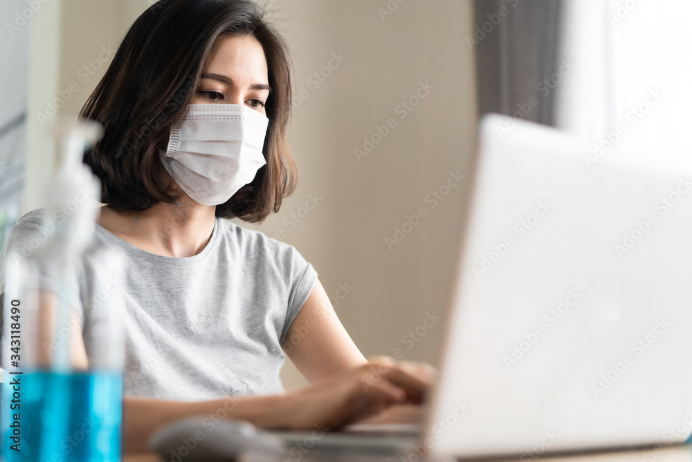 Asian young woman wearing mask work from home avoid Covid virus outbreak. Girl stay at house for self quarantine preventing from Coronavirus or Covid-19 virus pandemic. Social distancing concept.
