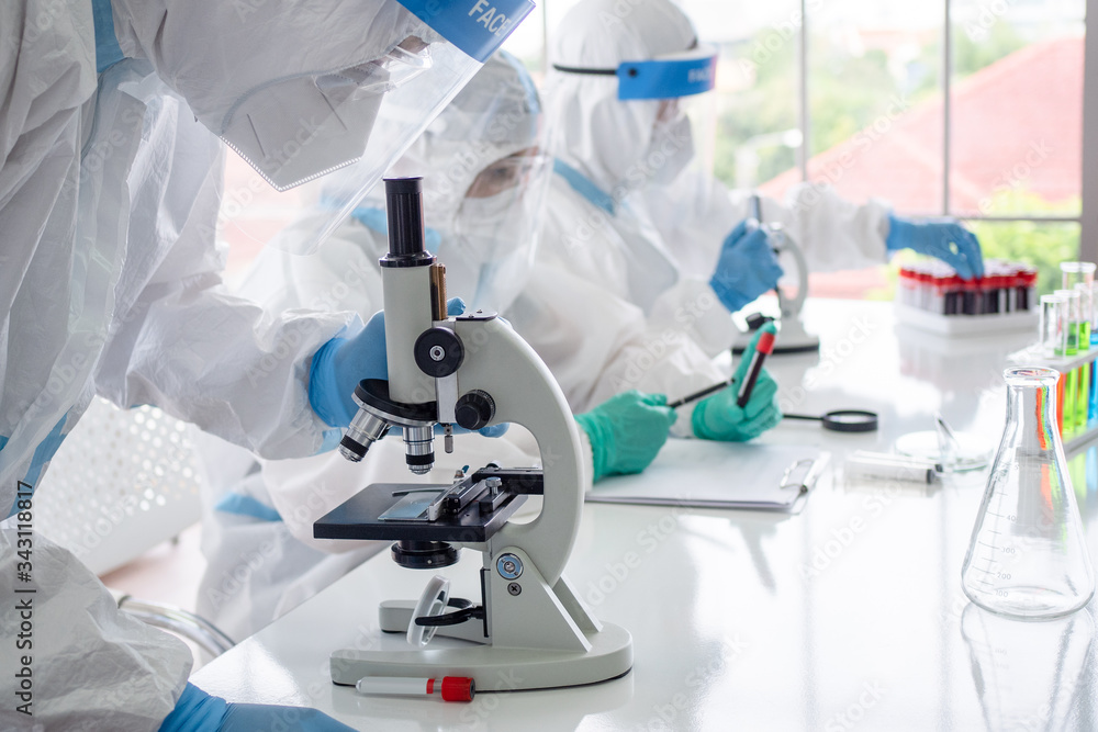 Scientists and microbiologists with PPE suit and face mask hold test tube and microscope in lab, finding treatment or vaccine for coronavirus infection. Covid-19, laboratory, and vaccine concept. Scientists and microbiologists with PPE suit and face mask hold test tube and microscope in lab, finding treatment or vaccine for coronavirus infection. Covid-19, laboratory, and vaccine concept.