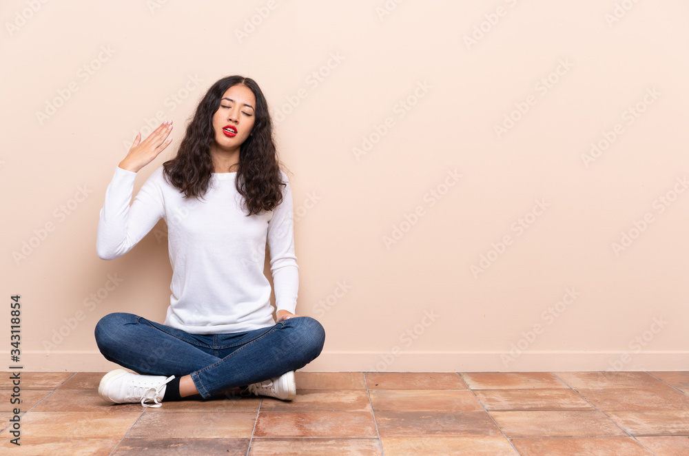 Young woman sitting on the floor with tired and sick expression