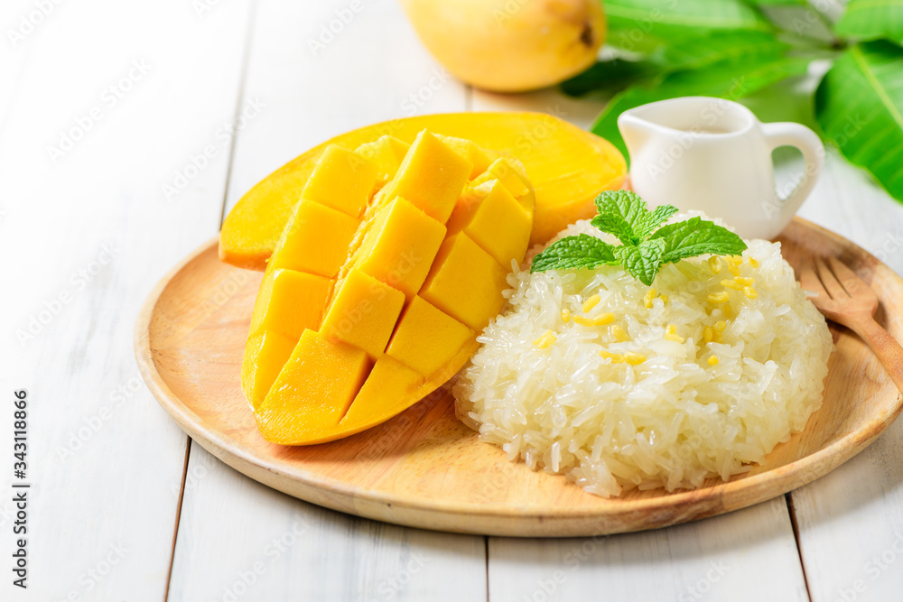 Ripe mango and sticky rice with coconut milk on white wood