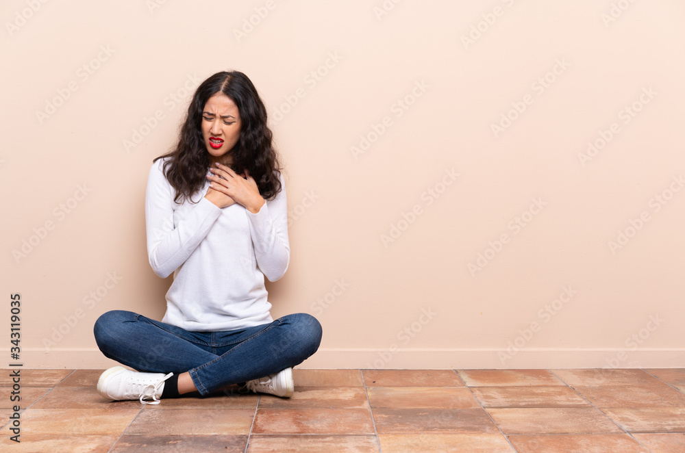 Young woman sitting on the floor having a pain in the heart Young woman sitting on the floor having a pain in the heart