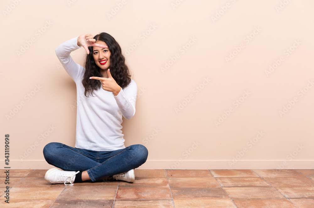 Young woman sitting on the floor focusing face. Framing symbol Young woman sitting on the floor focusing face. Framing symbol