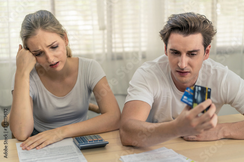 Obraz na plátne Stressed young Caucasian couples sitting with hand holding credit cards and look at bills worry about find money to pay credit card debt and all loan bills
