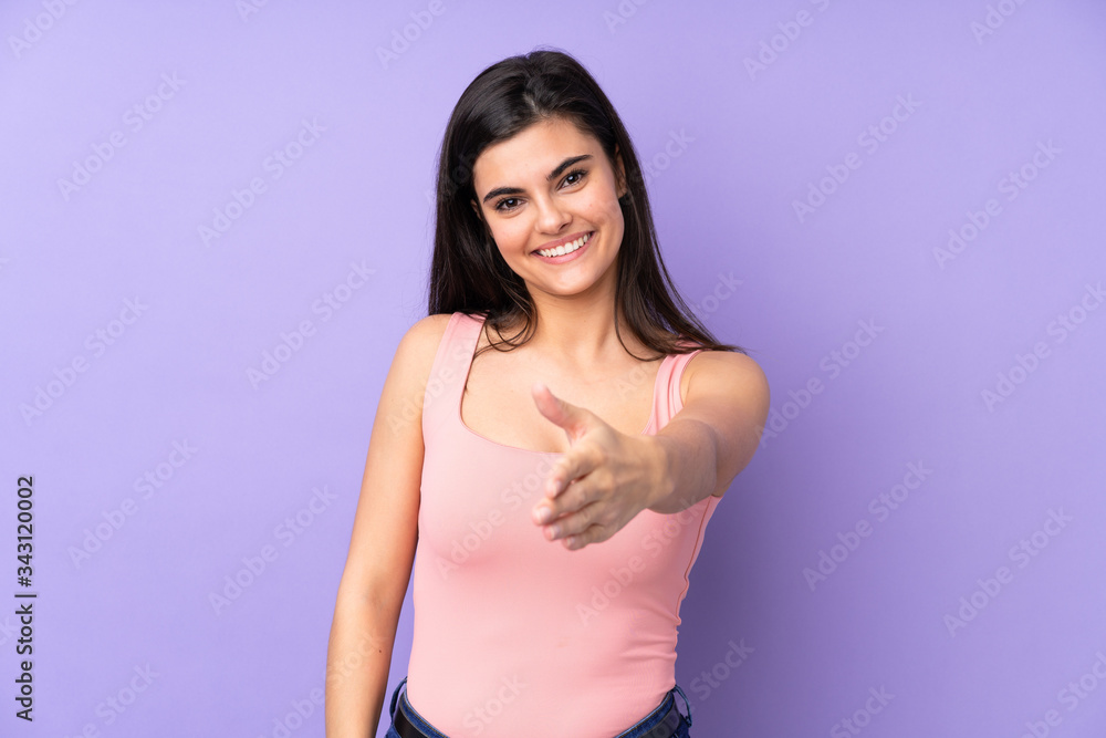 Young woman over isolated purple background shaking hands for closing a good deal Young woman over isolated purple background shaking hands for closing a good deal