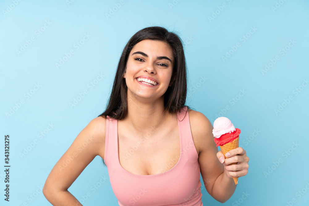 Young woman holding a cornet ice cream over isolated blue background Young woman holding a cornet ice cream over isolated blue background