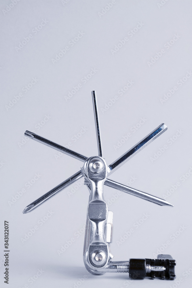 Old metallic unfold bike multi tool set with chain remover on a grey background. Bicycle multifunction hand tool like a mill. Vertical black and white monochrome. Old metallic unfold bike multi tool set with chain remover on a grey background. Bicycle multifunction hand tool like a mill. Vertical black and white monochrome.