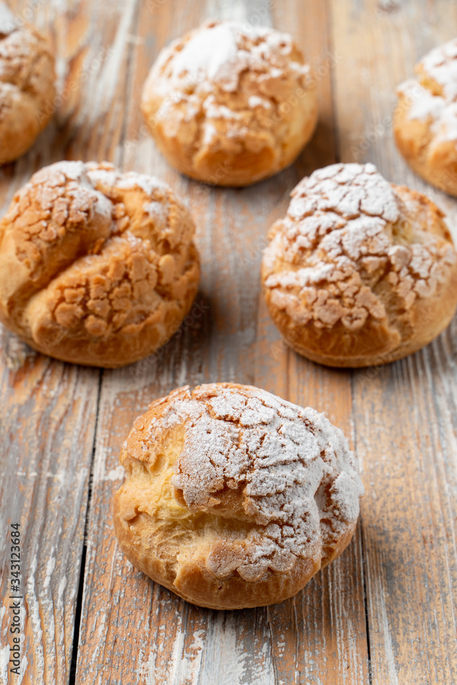Close up of golden crust profiterole stuffed with buttercream on vintage wooden table Close up of golden crust profiterole stuffed with buttercream on vintage wooden table