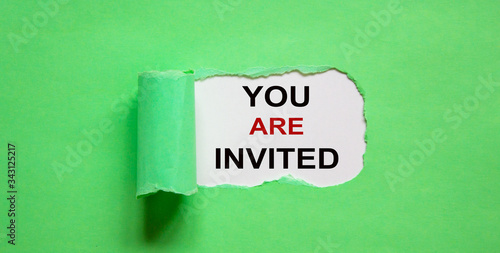 The text 'you are invited' appearing behind torn green paper.