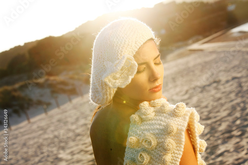 Bellissima Modella, vestita con un capo di lana bianca e basco bianco  , posa in un contesto di mare photo