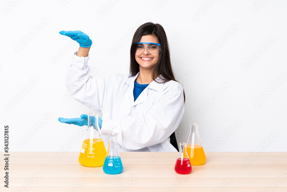 Young scientific woman in a table holding copyspace to insert an ad Young scientific woman in a table holding copyspace to insert an ad