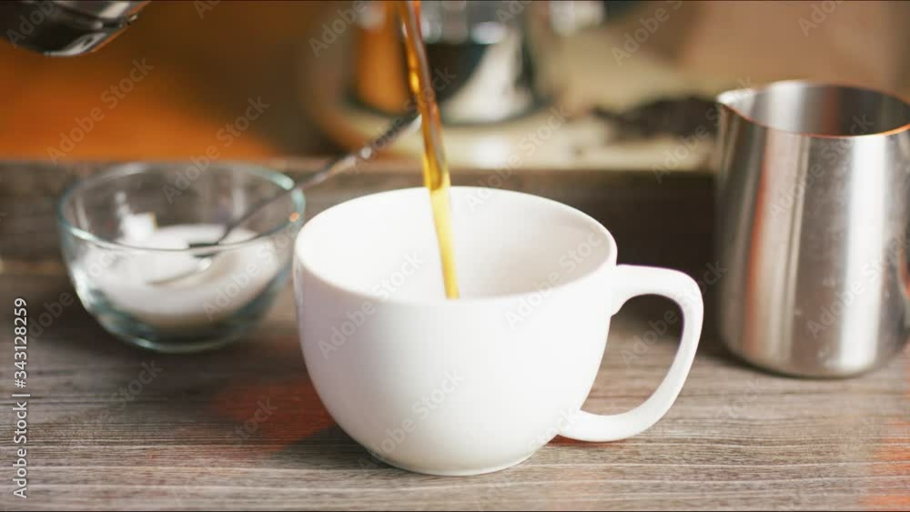 Pouring coffee in a white cup in real time with a slow dolly move. Pouring coffee in a white cup in real time with a slow dolly move.
