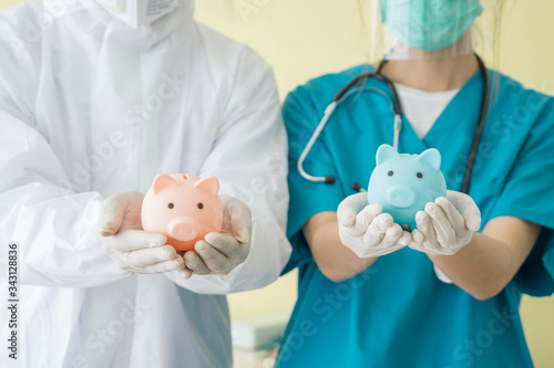 The doctor put on PPe clothes and put Adhesive shirt with the stethoscope holding piggy bank Health insurance symbol at The hospital,Business Insurance concept.