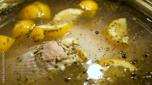 Raw Turkey soaked in cooking pot. Flavored brine of citrus, pepper, spices, herbs. Close-up Isolated.