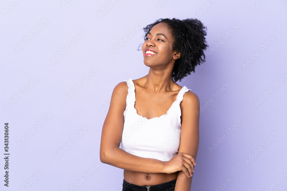 Young African American woman isolated on purple background looking to the side and smiling Young African American woman isolated on purple background looking to the side and smiling