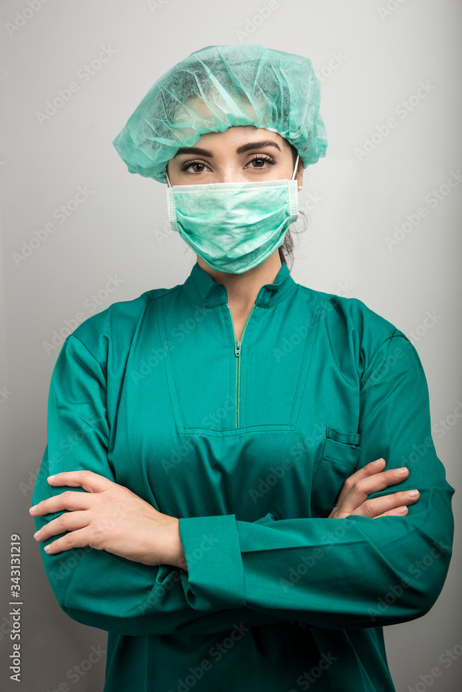 Dottoressa protetta per poter operare tiene le braccia conserte e guarda decisa, isolata su sfondo bianco Dottoressa protetta per poter operare tiene le braccia conserte e guarda decisa, isolata su sfondo bianco