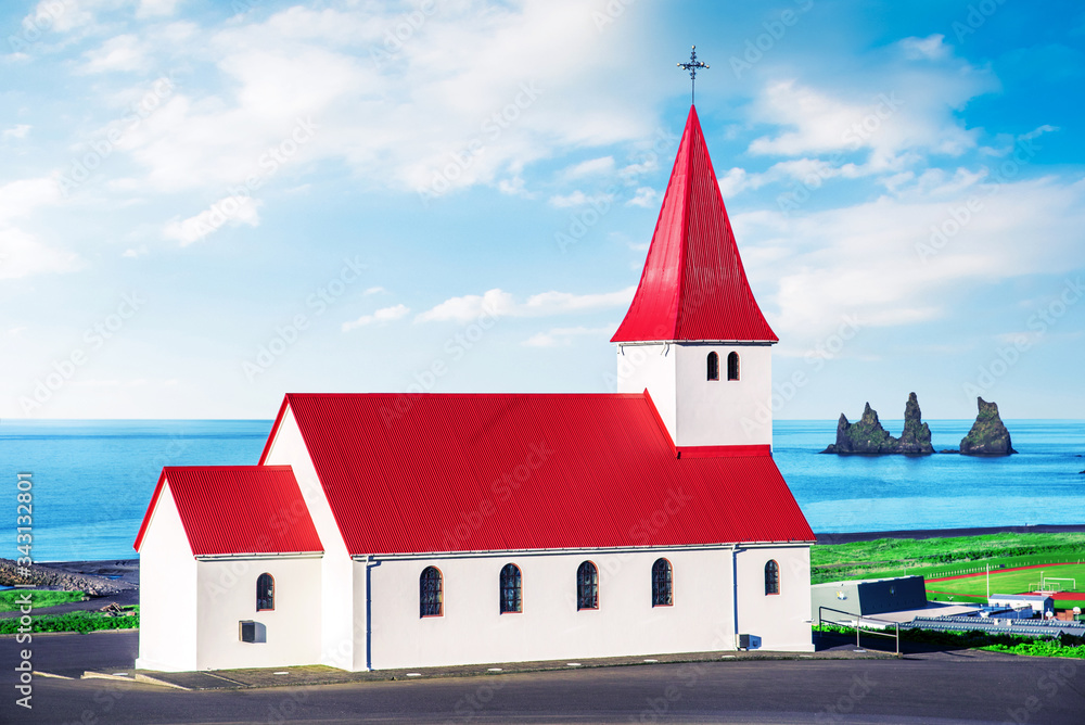 The famous Vik church (Vikurkirkja) on the background of the sea and the fingers of the troll in Iceland. place of pilgrimage. Impressive landscape. Exotic countries. Amazing places.