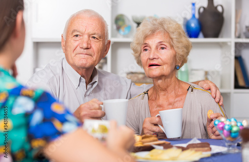 Happy mature couple drinking tea with female guest