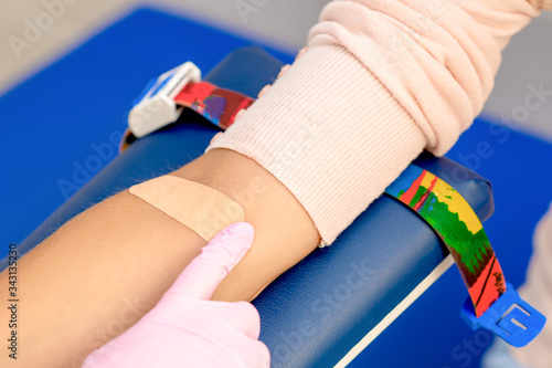 Nurse hand is glueing an adhesive plaster on arm, close up.