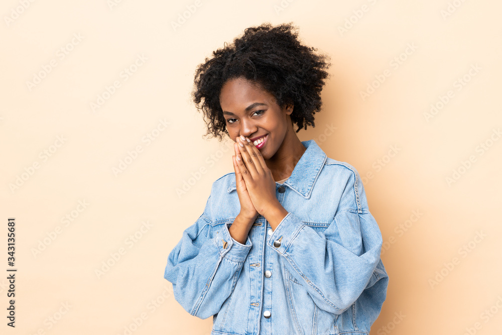 Young African American woman isolated on beige background keeps palm together. Person asks for something Young African American woman isolated on beige background keeps palm together. Person asks for something
