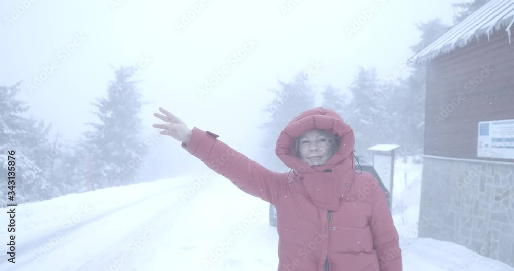 Portrait of Caucasian woman hitchhiking near broken car on snowy winter day. Lonely female driver standing on road with fir forest around. Travelling, tourism, accident, lifestyle. Cinema 4k ProRes HQ Portrait of Caucasian woman hitchhiking near broken car on snowy winter day. Lonely female driver standing on road with fir forest around. Travelling, tourism, accident, lifestyle. Cinema 4k ProRes HQ
