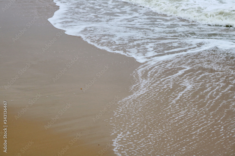 The ordinary photo of sandy beach and the sea wave with lots of white bubbles The ordinary photo of sandy beach and the sea wave with lots of white bubbles