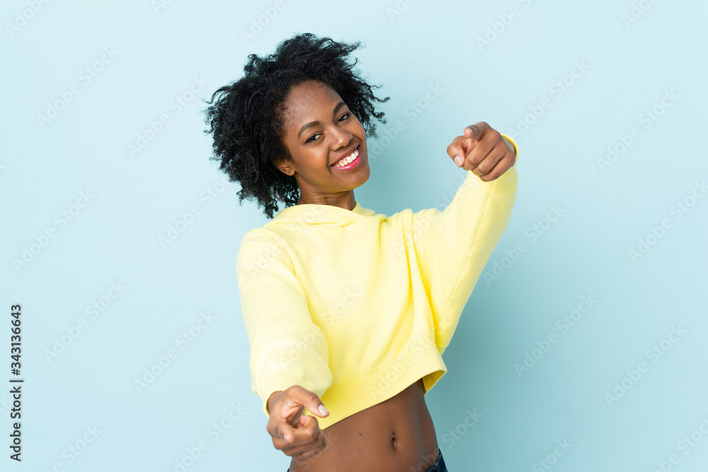 Young African American woman isolated on blue background pointing front with happy expression Young African American woman isolated on blue background pointing front with happy expression