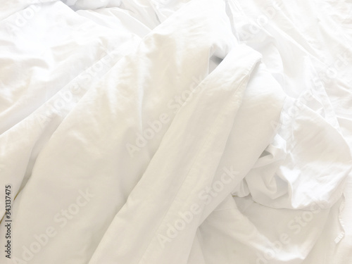 wrinkle messy blanket and white pillow in bedroom after waking up in the morning, from sleeping in a long night, details of duvet and blanket, an unmade bed in hotel bedroom with white blanket
