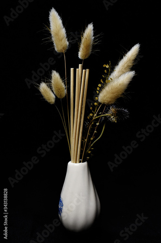 still-life. yellow spikelets in a white vase on a black background