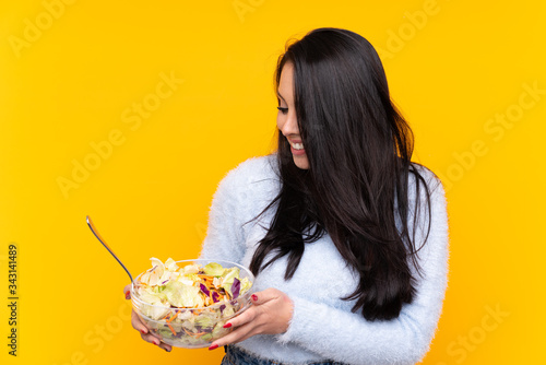 Young Colombian girl holding a salad over isolated background