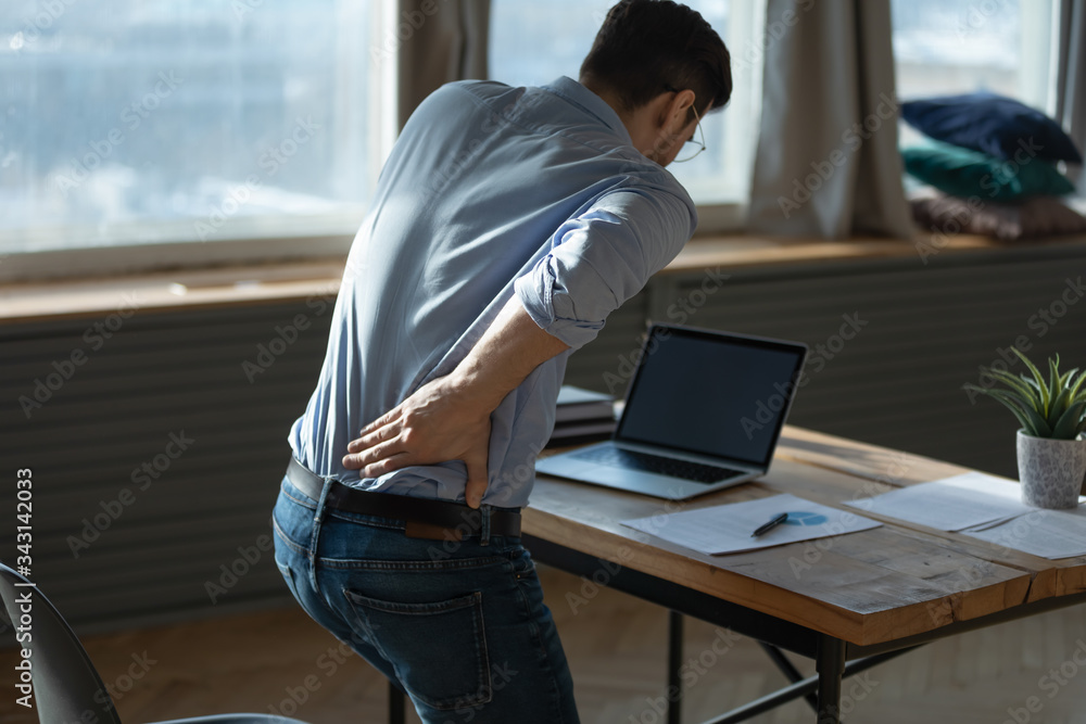 Rear view young man suffering from sudden backache, getting out of