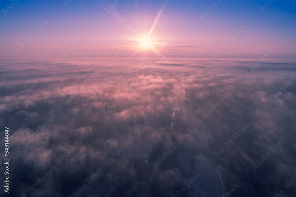 Early misty morning. Sunrise above the clouds. Rural landscape in early spring. Aerial view