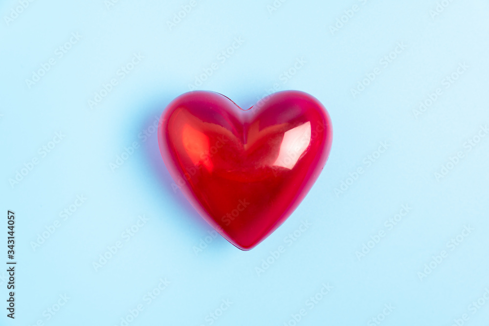 Red heart shape isolated on blue background for caring, love, valentine theme