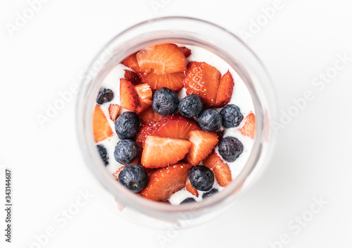 Delicious and natural glass with yogurt, oatmeal, strawberries, blueberries and milk all mixed ready to drink seen from above